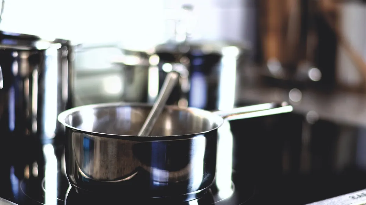 Panelas de inox sobre cooktop de vidro em cozinha